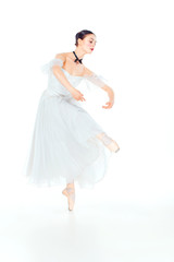 Naklejka premium Ballerina in white dress posing on pointe shoes, studio background.