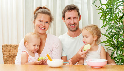 Mother and father Feeding her two daughters. Baby food. In the k