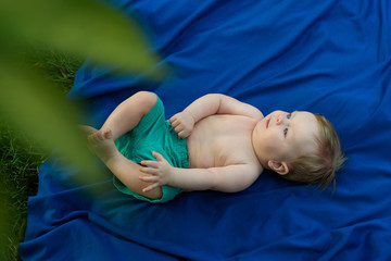 маленький мальчик на синем пледе в парке лежит на спине