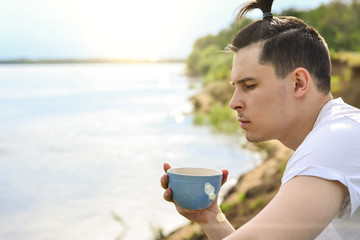Young man drinking coffee on the beach in Sunny summer day © ivan4es