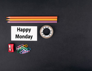 Happy Monday. Top view of a black ofice desk. Colored pencils, b