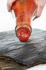 Tomato ketchup and ketchup bottle puring ketcup on a stone