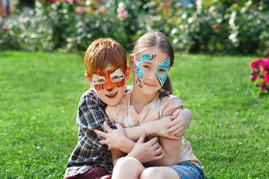 Happy children, boy and girl with face paint in park
