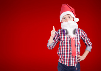 Confident little boy dressed up as Santa Claus poses with a set of headphones