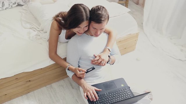 happy couple with laptop and card to buy online at home