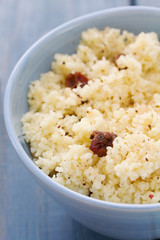 couscous with dry fruits on blue bowl on wooden background