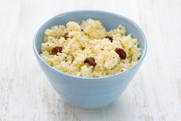 couscous with dry fruits on blue bowl on wooden background