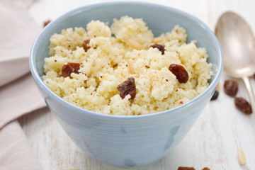 couscous with dry fruits on blue bowl on wooden background
