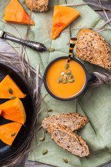 Pumpkin soup in a mug on rustic table