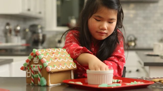 Young girl decorating gingerbread house for Christmas