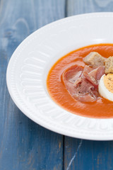 tomato cold soup with egg and jamon on white dish