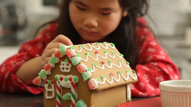 Closeup of young girl decorating gingerbread house for Christmas