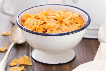corn flakes in white bowl on brown wooden background