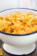 corn flakes in white bowl on brown wooden background