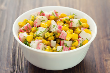 salad seafood with corn in white bowl on brown background