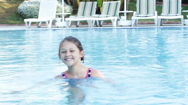 little girl swims in the pool 