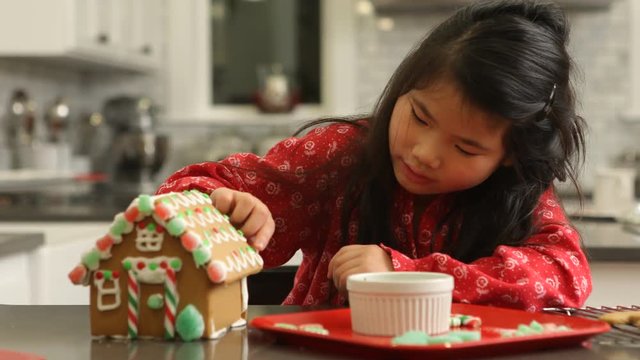 Young girl decorating gingerbread house for Christmas
