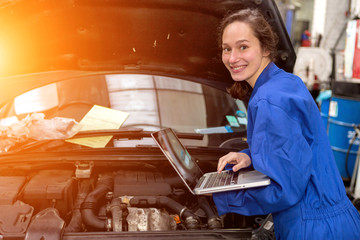 Young attractive woman mechanic working at the garage - obrazy, fototapety, plakaty
