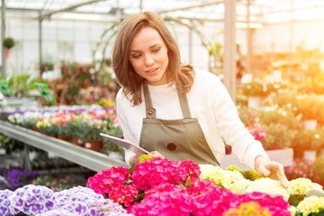 Young attractive woman working at the plants nursery using table