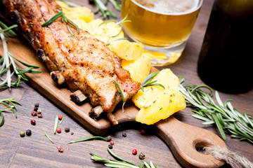 baked pork ribs with potatoes, rosemary and a glass of beer