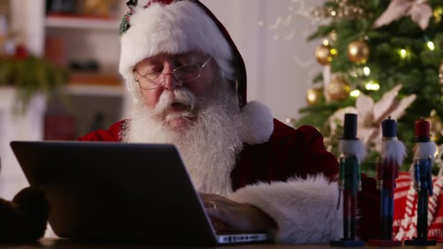 Santa Claus in workshop using laptop computer