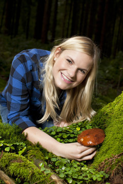 Junge Frau findet essbaren Pilz im Wald