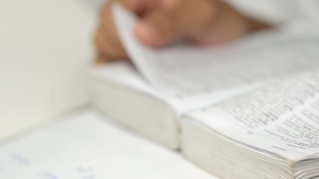 Little girl flips a page while reading a book (Dictionary)
