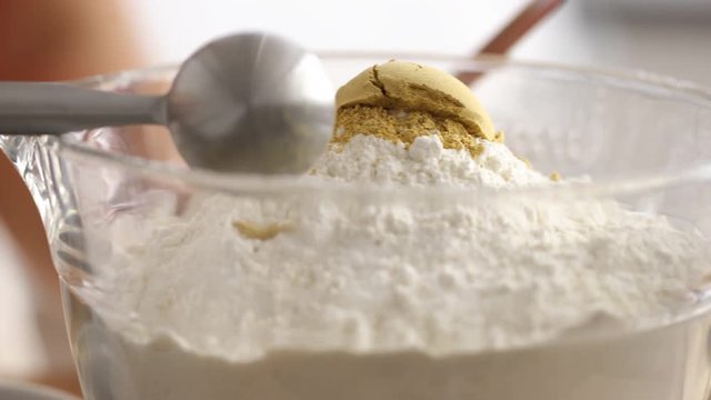 Measuring ground ginger into mixing bowl