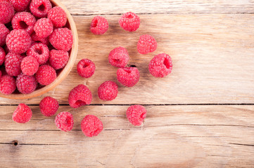 Fresh ripe raspberries in a bowl closeup on old wooden table. Summer berries background. Copy space. Top view