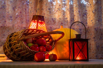 Still Life with Halloween characters - a basket with red apples, pumpkin and orange lantern.