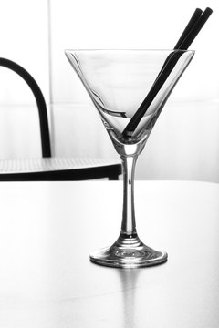 Solitudine, coppetta da cocktail vuota con due cannucce sul banco del bar,  bianco e nero, verticale Stock Photo | Adobe Stock