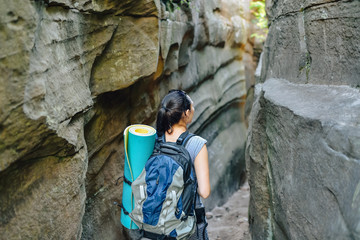 Woman Hiker Backpacker exploring narrow canyon in summer day, view from back