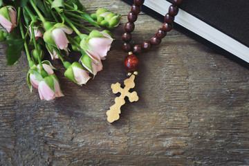 Wooden cross with flowers and book, closeup