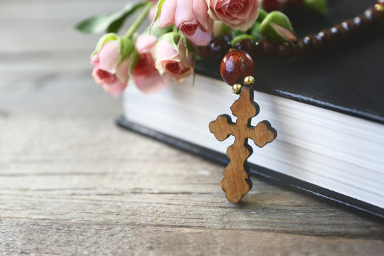 Wooden cross with flowers and book, closeup
