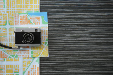 Vintage camera with map on wooden background