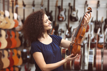 Beautiful girl with violin in music shop