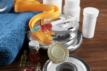 Dope in sports. Dumbbell, medal and drugs on wooden background