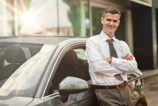 Businessman posing with his car