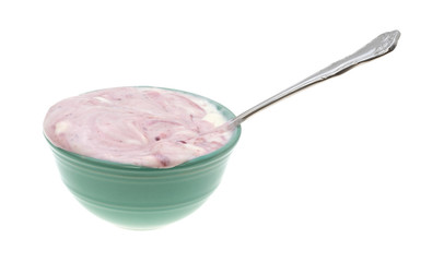 Raspberry yogurt in a bowl with a spoon isolated on a white background.
