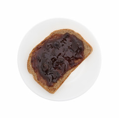 Plate with plum preserves on wheat bread isolated on a white background..
