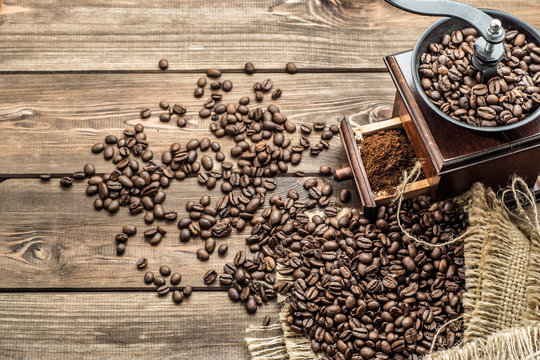 Coffee grinder and coffee beans in jute sack on wooden background