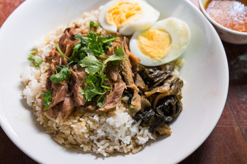 Stewed pork leg on rice on wooden table