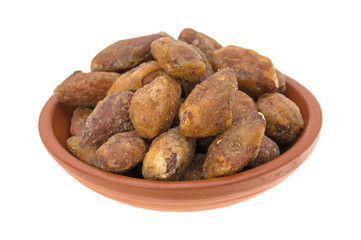 Honey glazed almonds in a small bowl isolated on a white background.