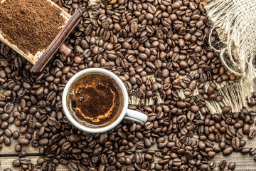 Cup of coffee and coffee beans on wooden table, overhead
