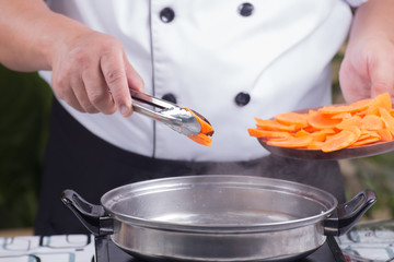 Chef putting carrot for cooking