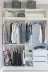 clothes hanging on rail in modern white wardrobe