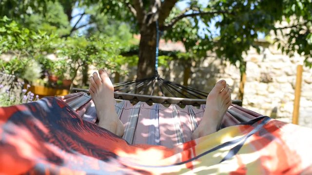 Man lying in a hammock in the garden, real time, no sound,