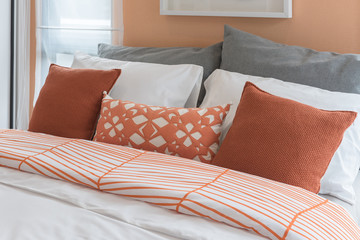 Fototapeta na wymiar orange color tone pillows set on bed in modern bedroom