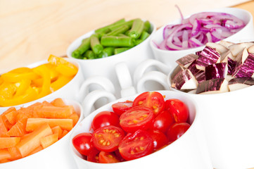 Cut vegetables in white bows arranged in rainbow colors 