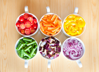 Cut vegetables in white bows arranged in rainbow colors 